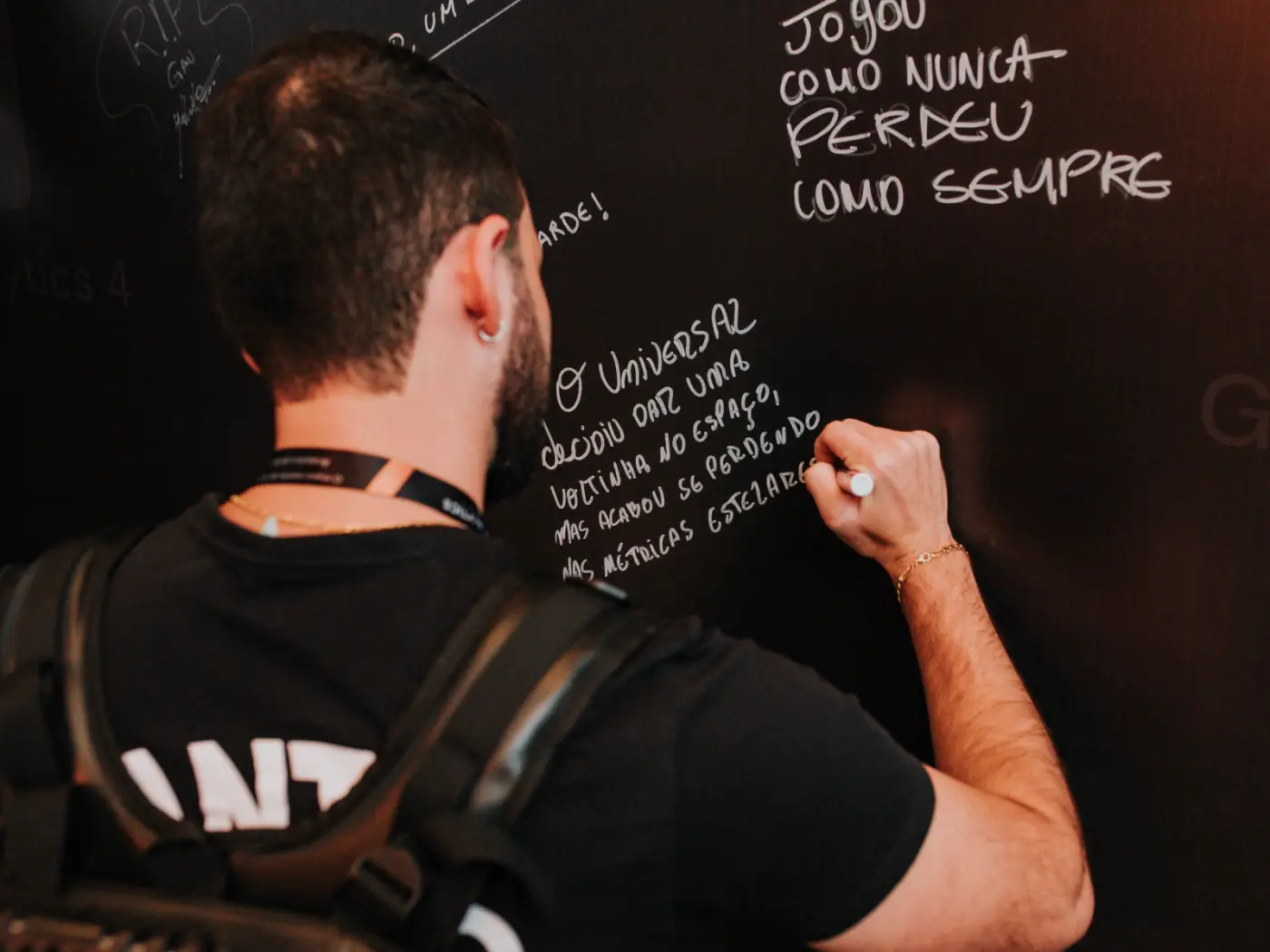 Participante escrevendo no mural interativo do evento